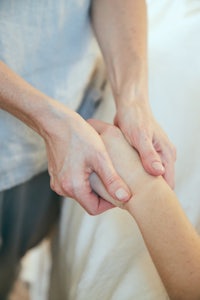 a person is holding a person's hand on a bed